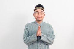Asian Muslim man smiling doing greeting pose during Ramadan