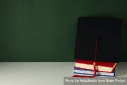 Graduation hat with books on a table on a dark background. bYqRJ1