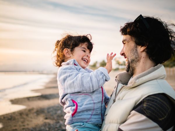 father holding little daughter at the beach