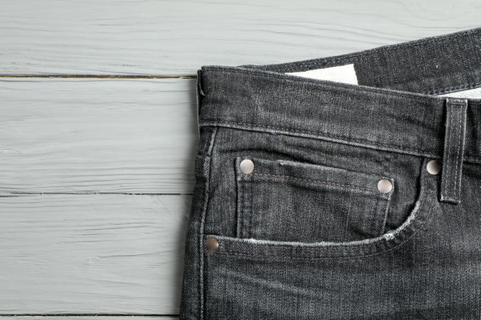 Jeans pocket on wooden background, space for text