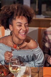 Cheerful Black woman eating in restaurant