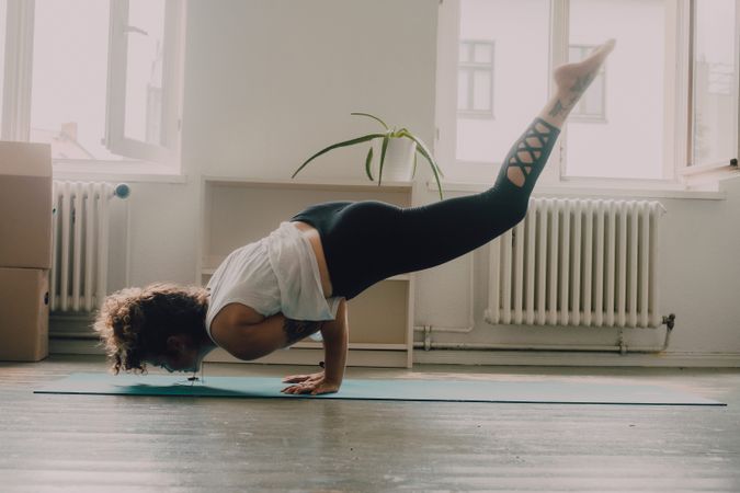 Calm woman practicing yoga pose and balancing on hands at home