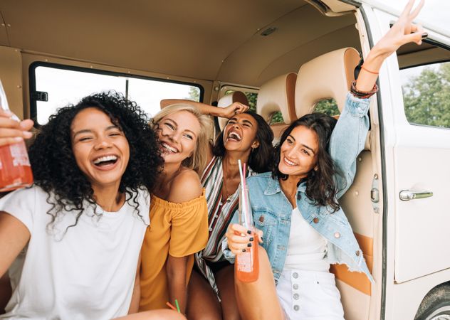 Joyful woman having drinks and fun in the back of a van