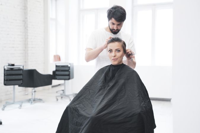 Hairdresser cuts woman's hair with scissors