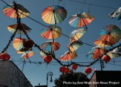 Rainbow umbrellas and red lanterns hung up on lines over street in Barrio Chino beZvp0