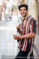 Happy male in striped shirt standing in the streets of Granada, Spain with coffee 5kRrr6