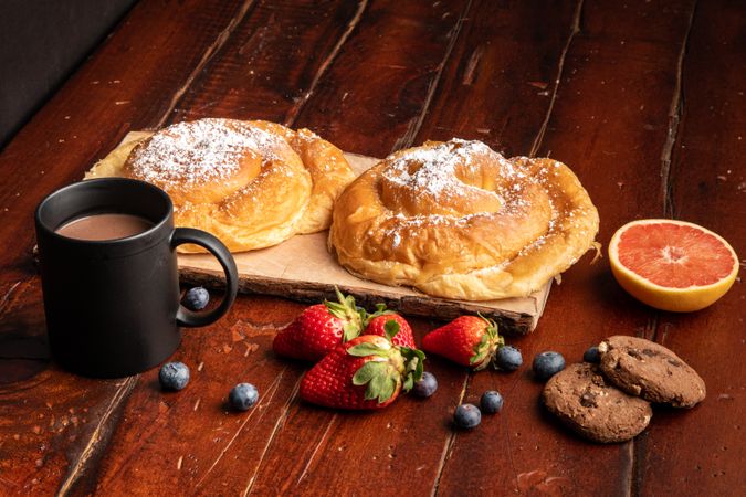 Fresh fruits near bun and hot drink