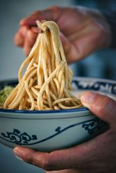 Crop man with noodles on chopsticks above delicious ramen