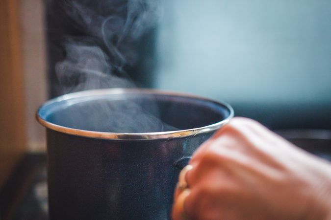 Crop hand with steamy mug