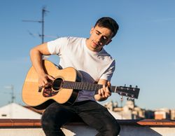 young man sitting playing acoustic guitar on a rooftop