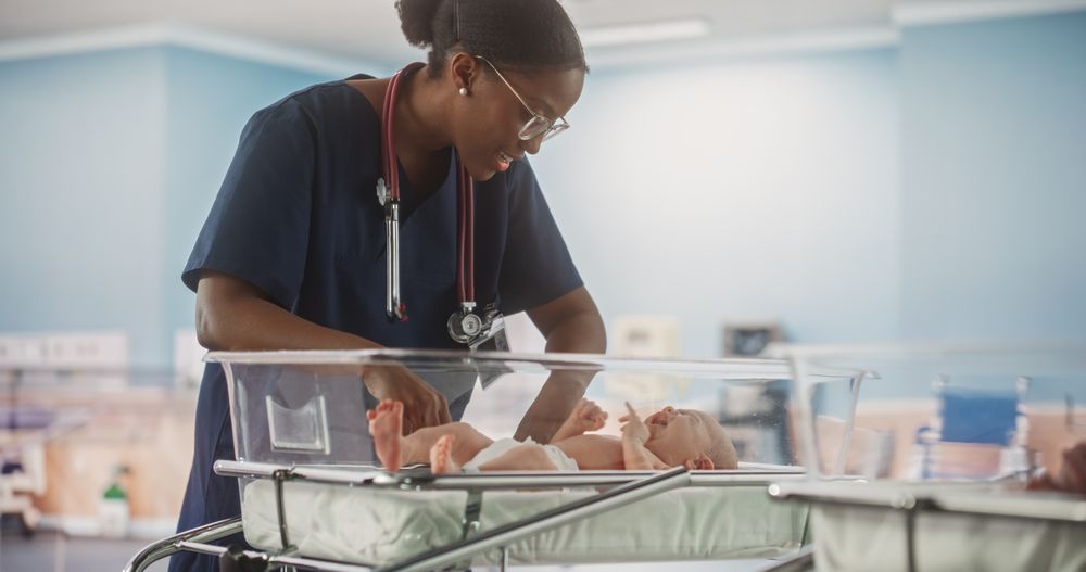 Professional Black Nurse Soothing an Adorable Small White Newborn Child in Nursery Clinic.