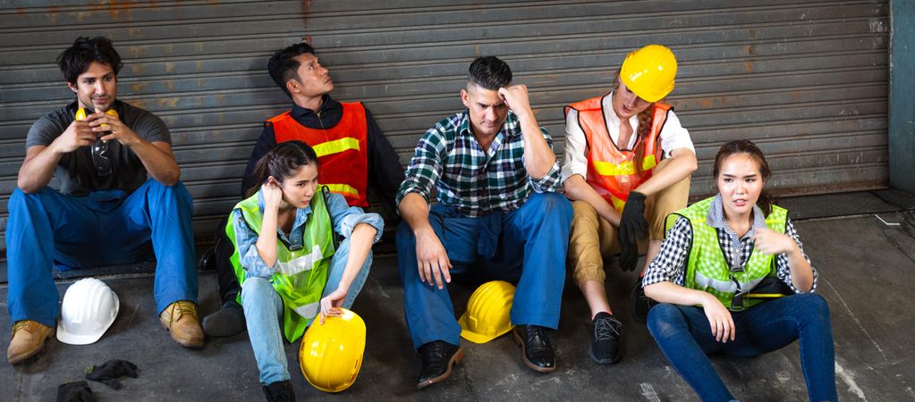 Group of people in PPE gear waiting around factory