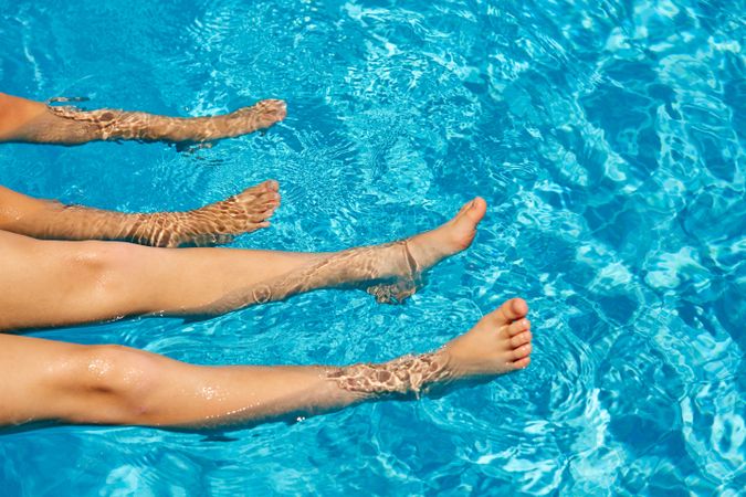 Faceless children lounging in swimming pool