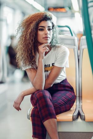 Portrait of serious Arab woman sitting in train carriage resting hand on chin