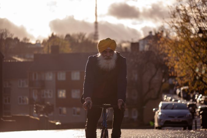 Mature Sikh man in turban cycling through British town