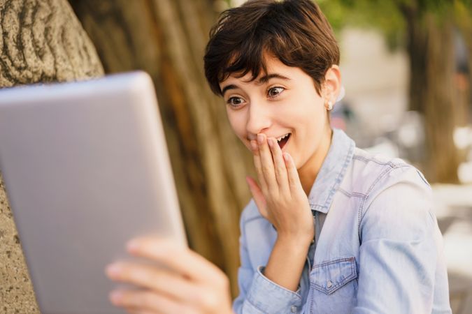 A Young Woman is Expressing Surprise and Delight in Reaction to Her Tablet Screen Display
