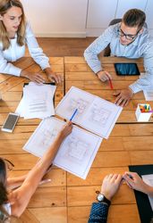 Top view of architects in a work meeting looking at construction drawings
