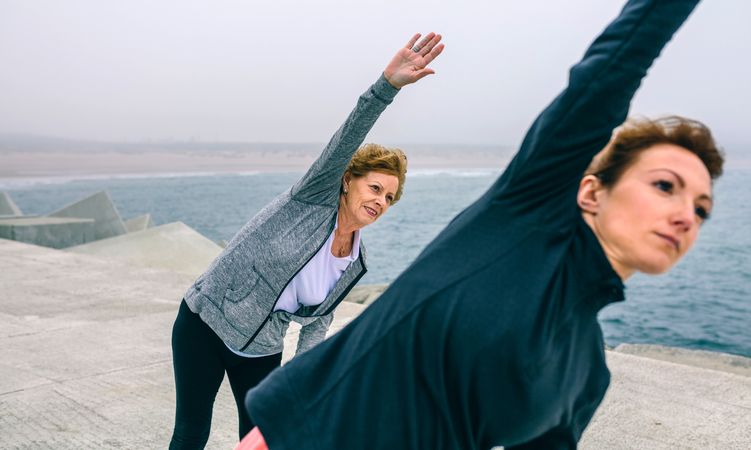Older woman stretching side with coach