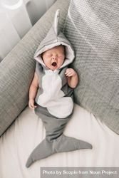 Baby in shark costume sleeping on couch bE7M75