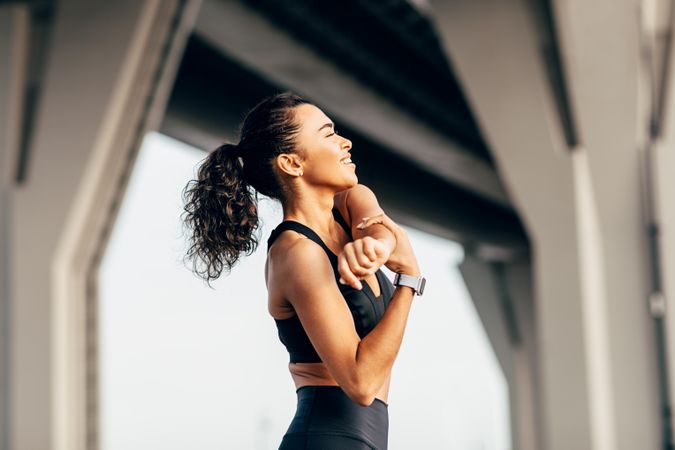 Happy female stretching arm outdoors