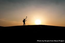 Silhouette of person with backpack on hill during sunset 0VL3G4