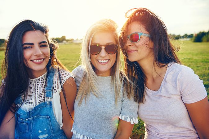 Happy female friends sitting in sunny field
