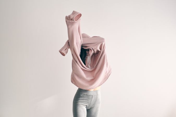 Woman covering face with sweater in studio