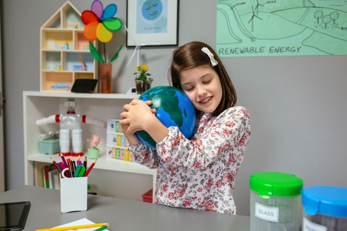 Female student hugging a handmade globe world at ecology classroom