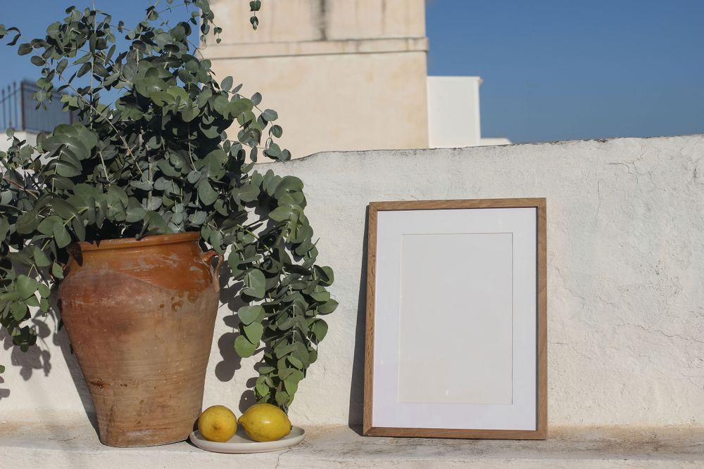 Empty vertical wooden frame picture mockup against old textured wall in sunlight.