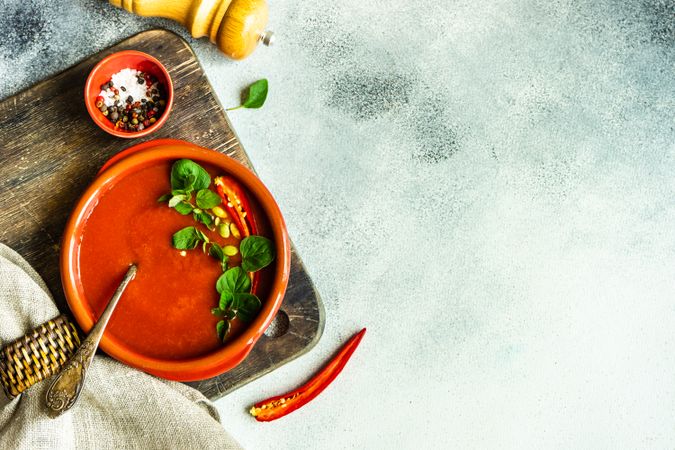 Top view of tomato soup in ceramic bowl on wooden board with copy space