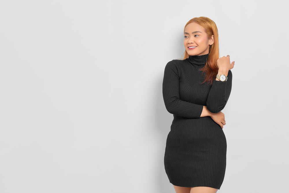Happy Asian woman with red hair in dark dress in studio shoot looking to the side with copy space
