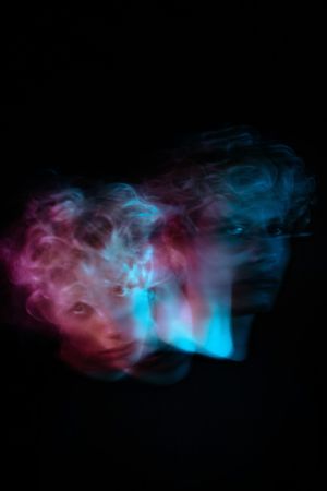 Blurry portrait of blonde young man with uv hair dye against dark background