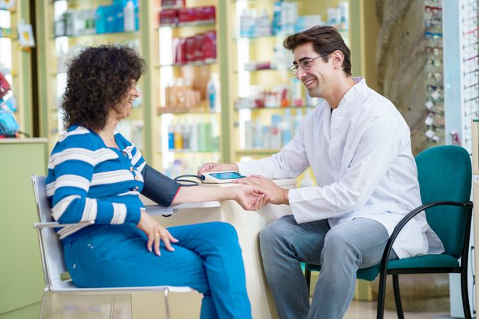 Cheerful pharmacist and woman customer in pharmacy