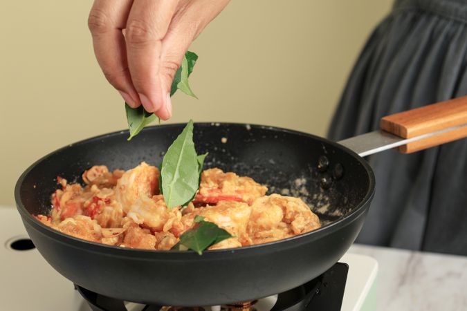 Female Hand Put Curry Leaf to the Pan with Stir Fry Prawn.