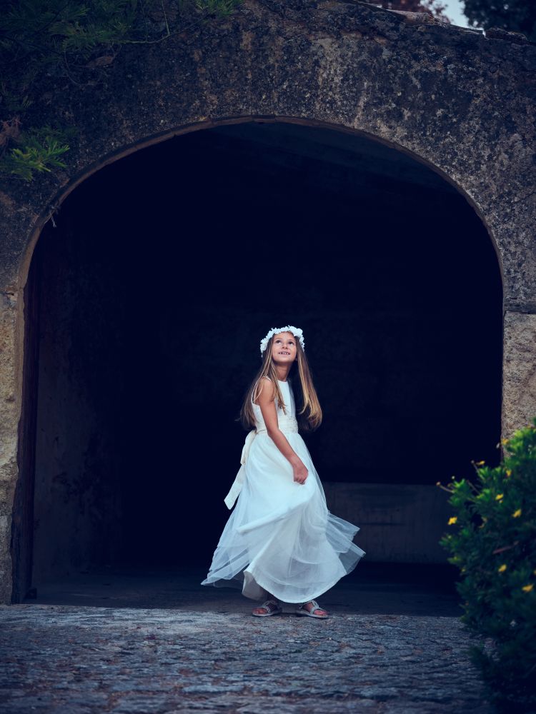Elegant woman in elegant dress standing near arched wall entranc