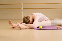 Ballet dancer performing forward stretch during warm-up.