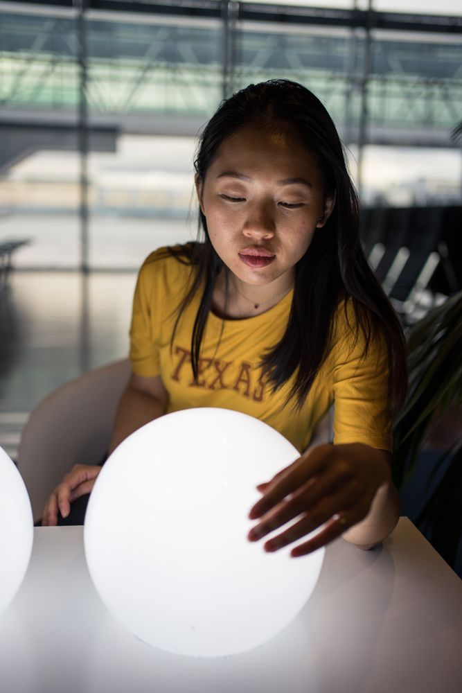 Asian woman examining round lamps on table