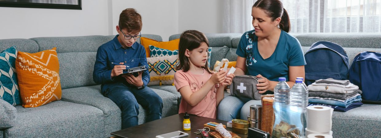 Mother preparing emergency backpack with her children