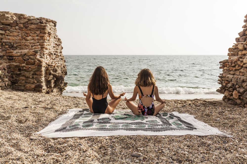 Young females meditating on sandy beach