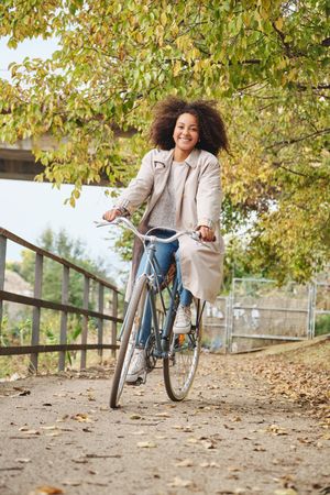 Happy Black female enjoying bike ride in park