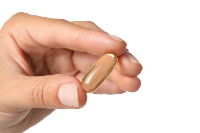 Omega pills in hand, isolated on blank background