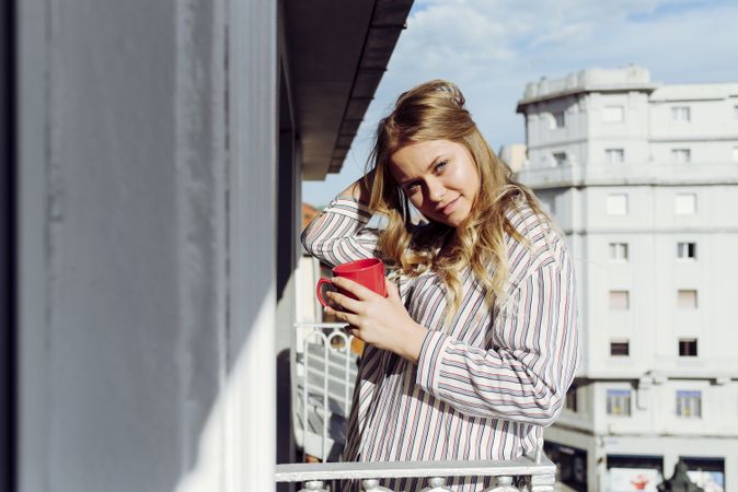 Young cheerful female with cup on terrace