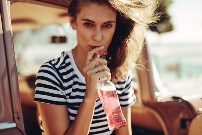 Female drinking refreshing soft drink in the car