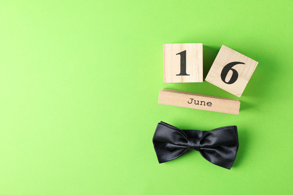 Wooden cubes calendar date June 16 and bow tie on color background, space for text