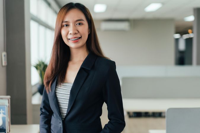 Asian woman with dental braces smiling in her office
