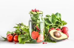 Green salad in jar with ingredients: green lettuce leaves, tomato, strawberry, avocado, cucumber and pomegranate seeds