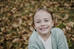 Smiling girl between meadow with dry leaves