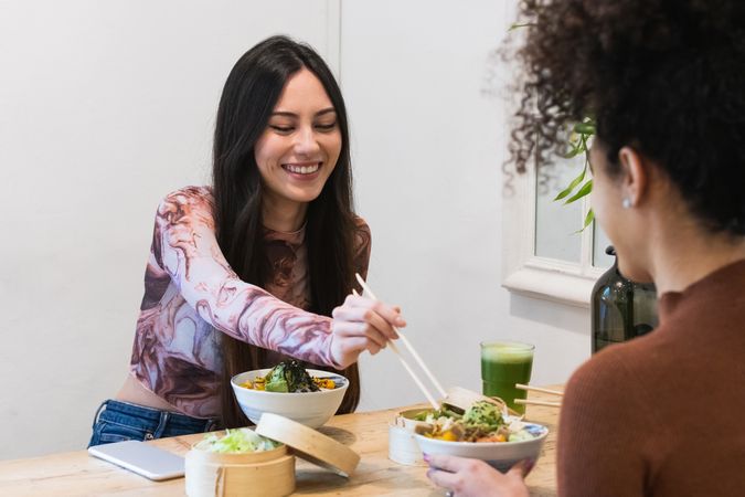 Delighted friendly multiethnic women eating in restaurant