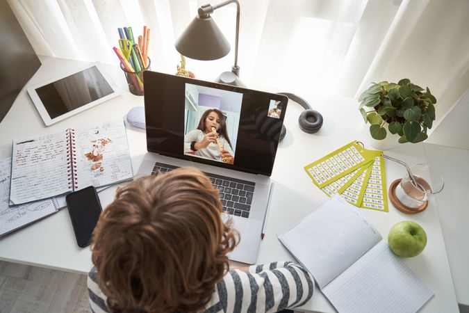 Boy video chatting on laptop with girl playing flute
