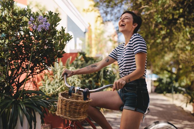 Cheerful woman with her bike laughing outdoors